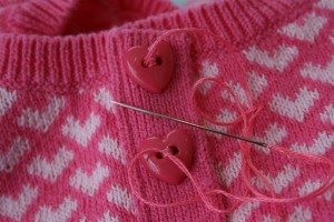 pink sweater with heart buttons and needle