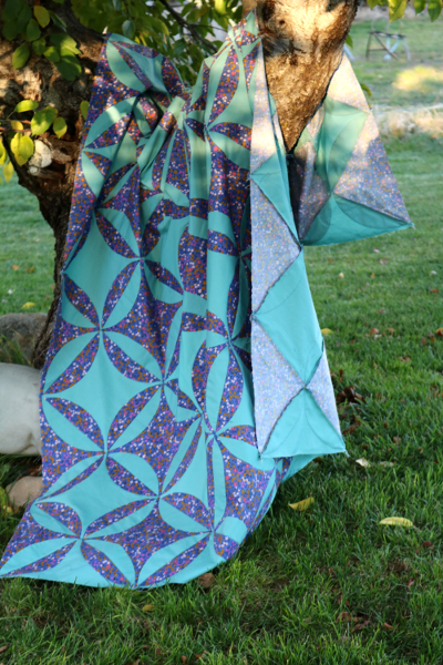 blue and teal orange peel quilt draped over tree branch